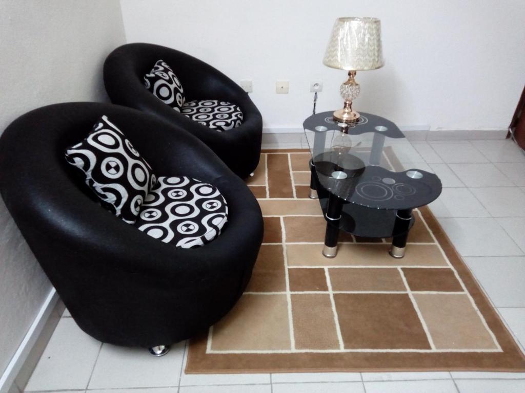 Dos sillas negras y una mesa en una habitación en Appartement ABS, en Abiyán
