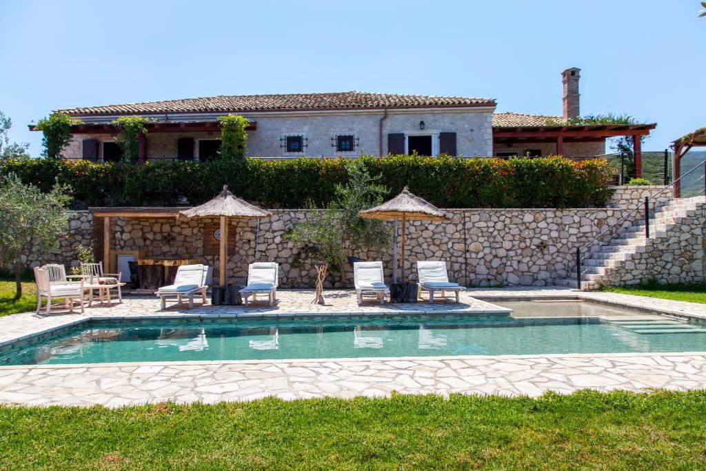 a pool with chairs and umbrellas in front of a house at Traditional Villa Fioretta in Mármaron
