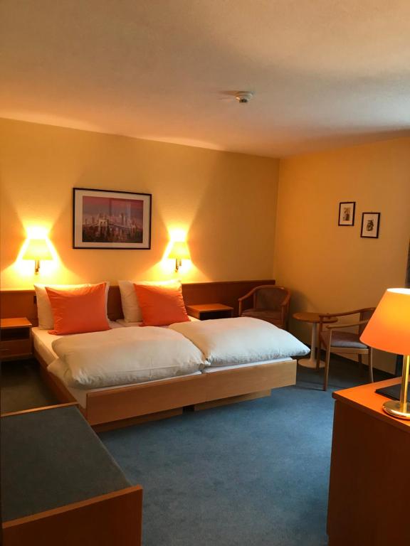 a hotel room with a bed with orange pillows at Hotel Eintracht in Oberbipp