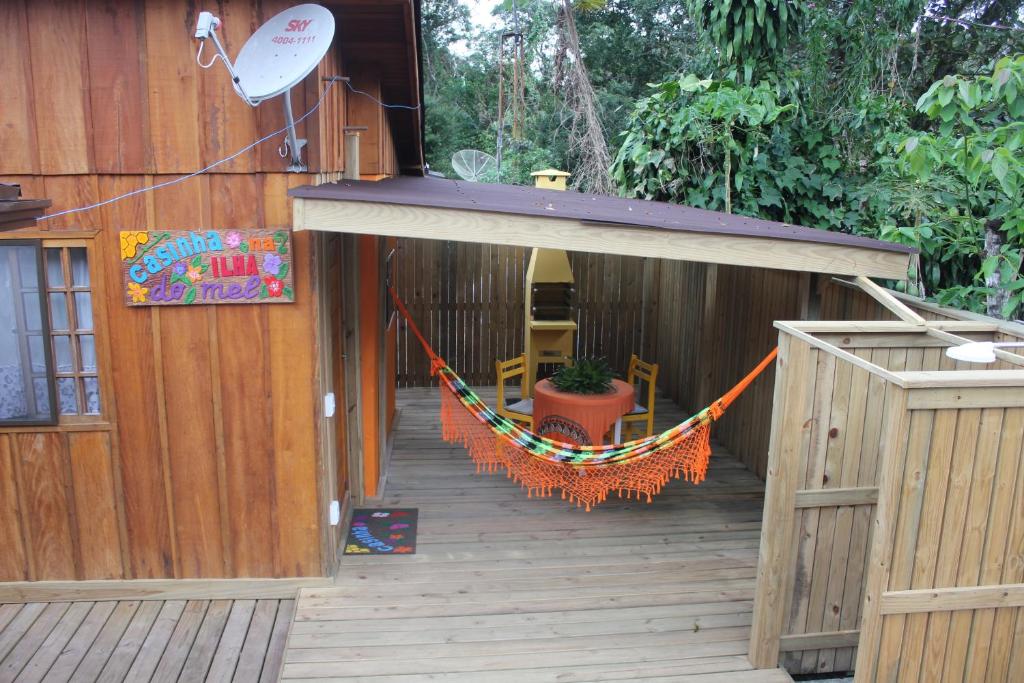 eine Veranda mit einer Hängematte auf einer Holzterrasse in der Unterkunft Casinha na Ilha do Mel - Pr in Ilha do Mel