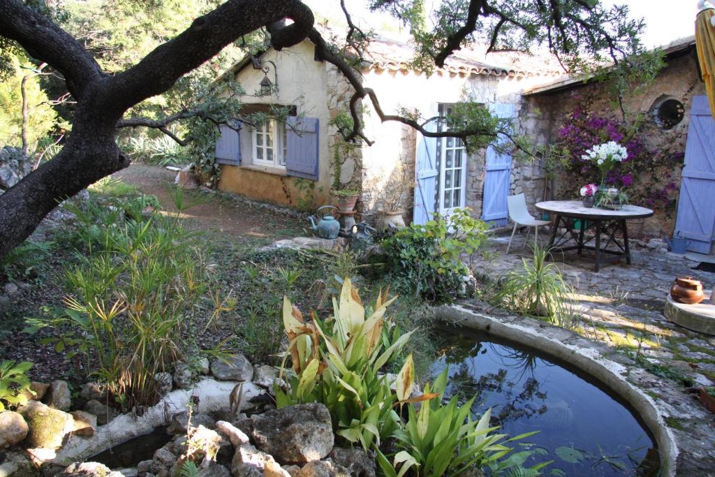 un jardín con un estanque frente a una casa en la maison bleue en Carros