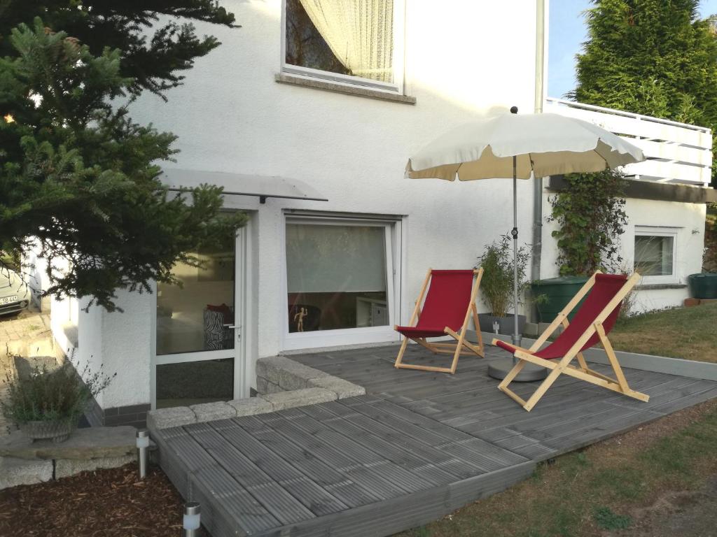 zwei Stühle und ein Regenschirm auf einer Holzterrasse in der Unterkunft Ferien-Appartement Goldhausen in Goldhausen