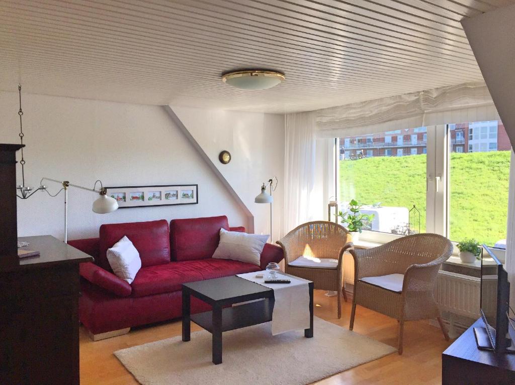 TwielenflethにあるFabys Ferienwohnungのリビングルーム(赤いソファ、椅子付)