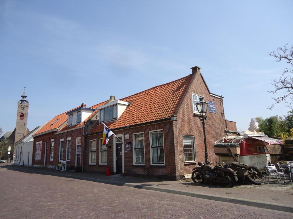 un edificio de ladrillo con un barco estacionado frente a él en t Laege Uus en Burgh Haamstede