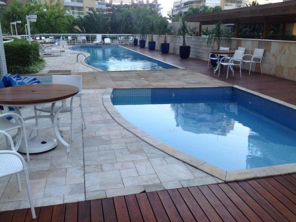a swimming pool on a deck with a table and a table and a tablespect at Lindo ap dentro da riviera mód 8 pertinho da praia área de lazer completa in Riviera de São Lourenço