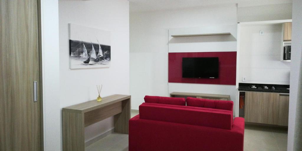 a living room with a red couch and a tv at Flats Dunas Cabo Frio in Cabo Frio