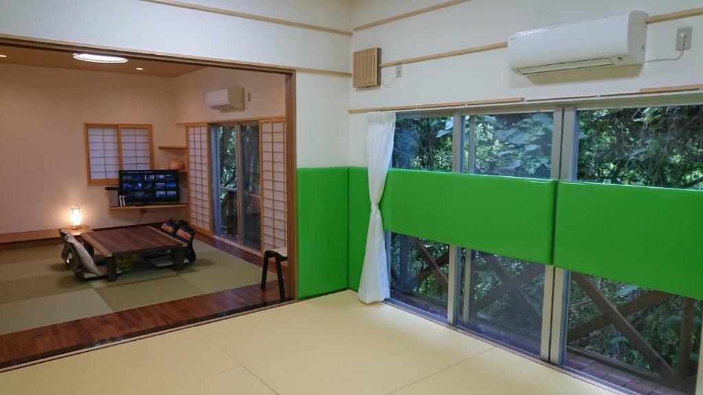 a room with large windows and a room with a table at Big Tree JUDO ハウス in Urasoe