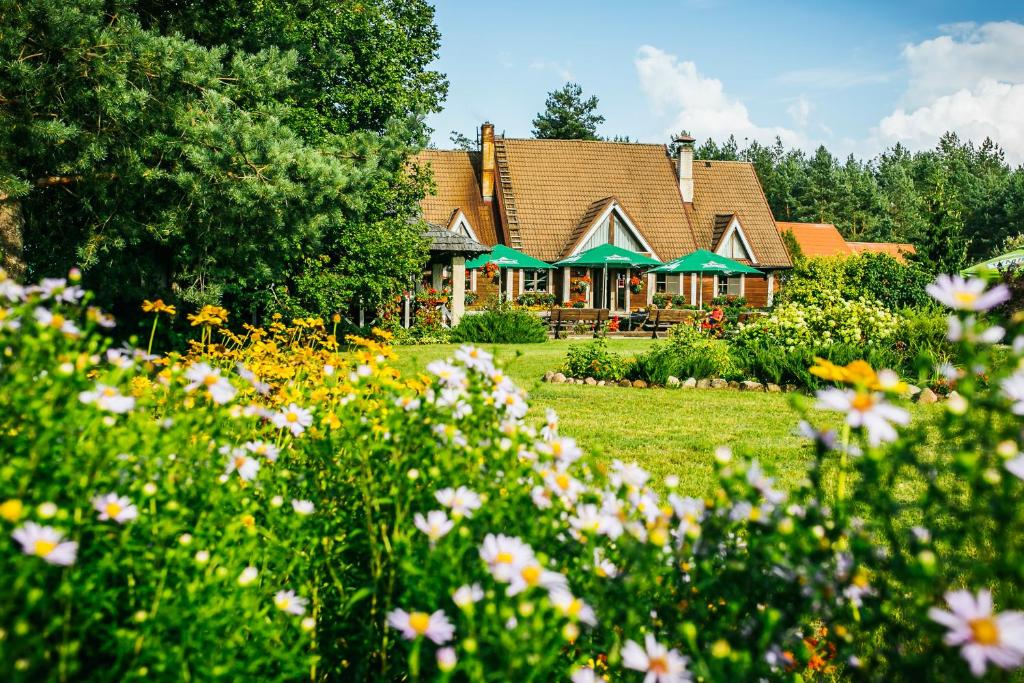 ein Haus mit einem Blumenfeld davor in der Unterkunft Pirčiupio Karčema in Pirčiupiai