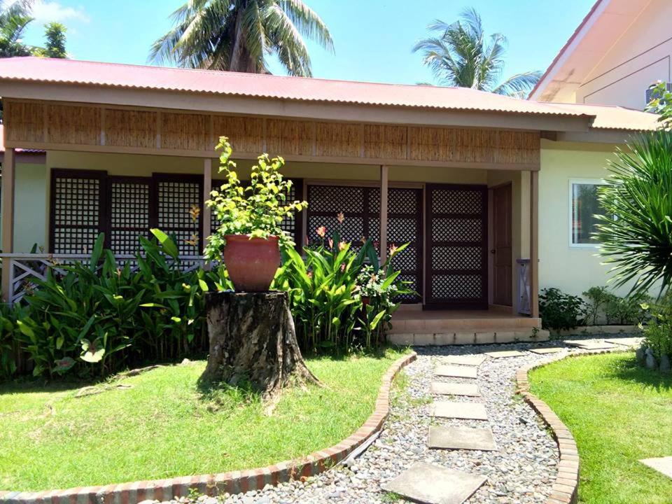 uma casa com um vaso de flores num toco de árvore em Happy Ripples Beach Resort em Mabilao