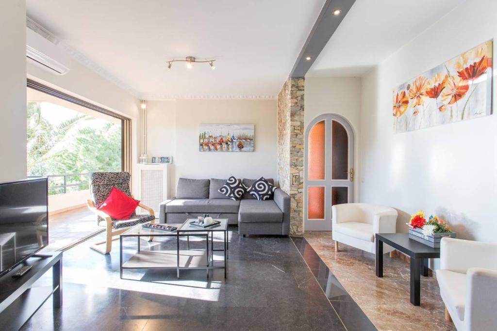 a living room with a couch and a tv at Modern Condo at the Beach in Sounio