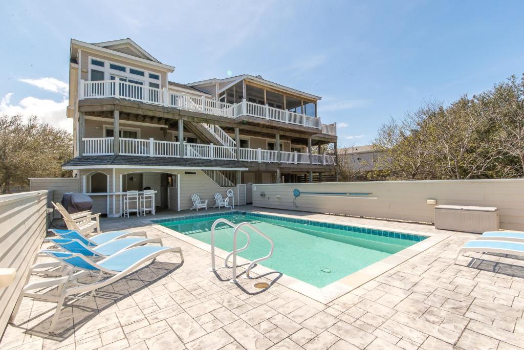 a house with a swimming pool and some chairs at Beach Cabana in Southern Shores