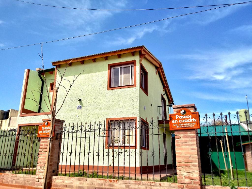 une maison avec une clôture et un panneau devant elle dans l'établissement Casa en Mina Clavero, à Mina Clavero