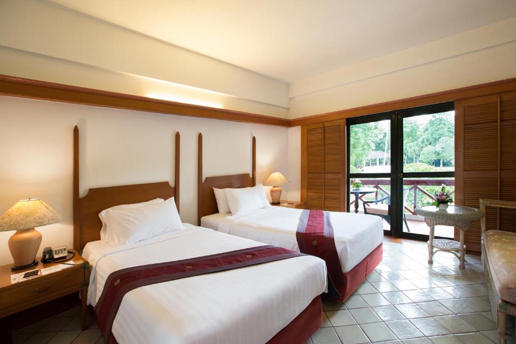 a hotel room with two beds and a balcony at The Imperial Chiang Mai Resort & Sports Club in Chiang Mai