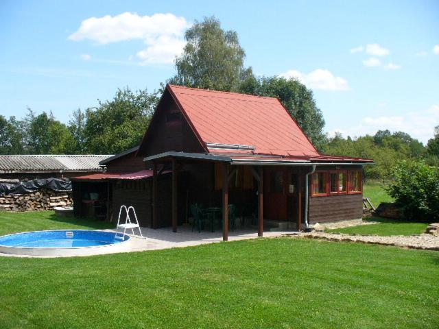 uma casa com um telhado vermelho e uma piscina em CHATA STRÁŽ em Stráž nad Nežárkou