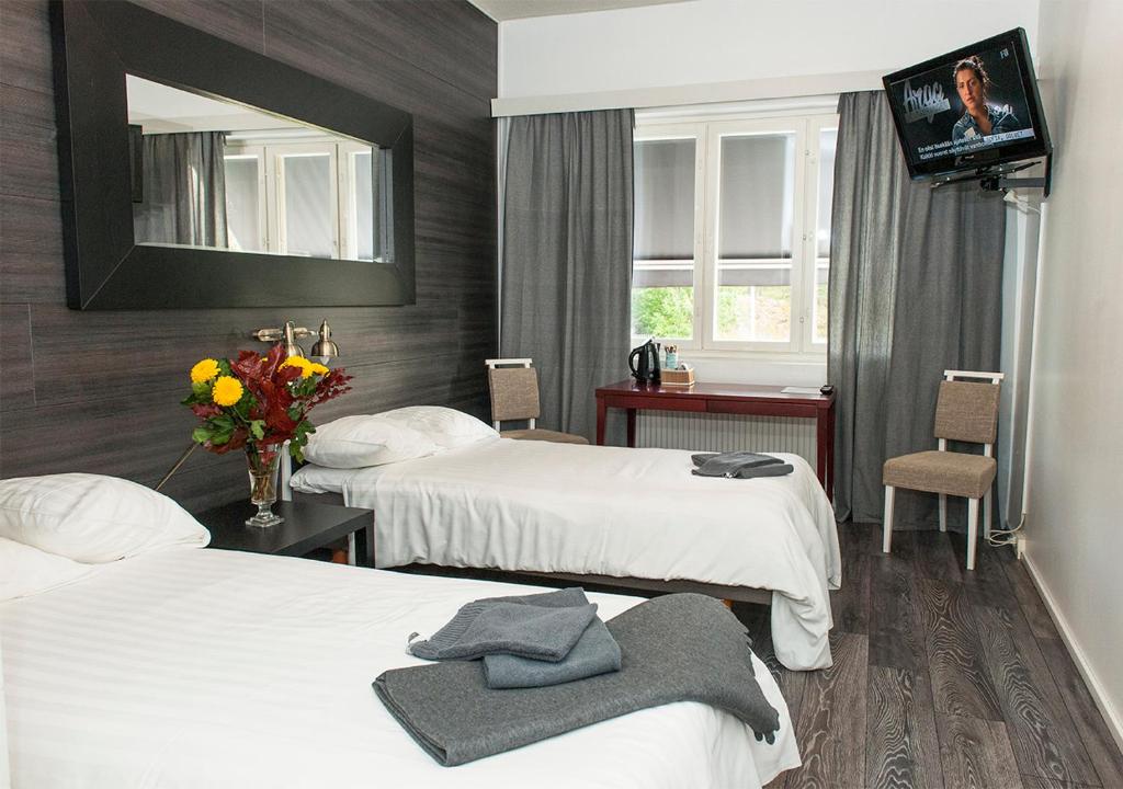 a hotel room with two beds and a television at Hotelli & Ravintola Martinhovi in Raisio