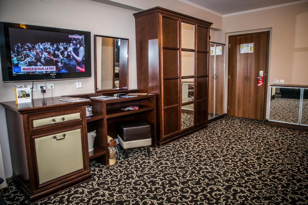una sala de estar con TV y una habitación grande en Hotel Megalos, en Constanţa