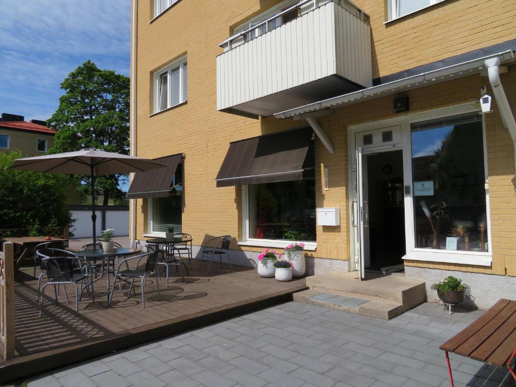 eine Terrasse mit einem Tisch, Stühlen und einem Sonnenschirm in der Unterkunft Alléhotellet in Finspång