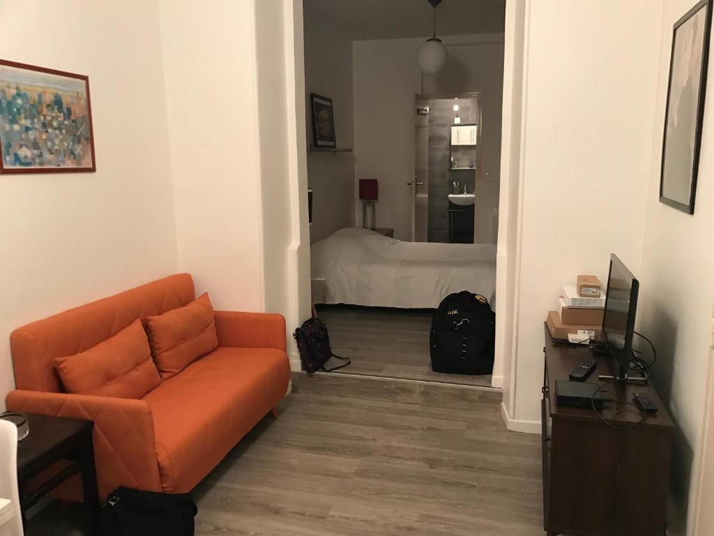 un salon avec un canapé orange et une chambre dans l'établissement Notre Dame de Lorette 75009 Paris, à Paris