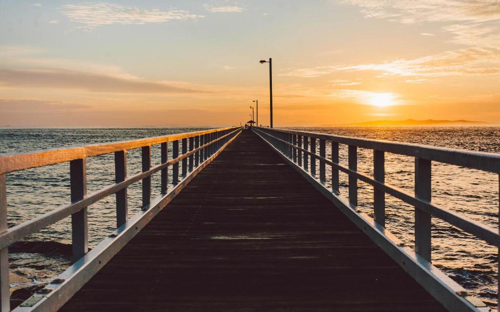 a pier stretches out into the ocean at sunset at Point Lonsdale 1 Bedroom Apartment in Point Lonsdale