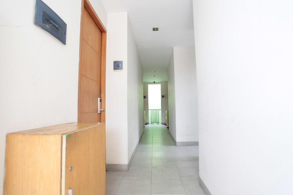 un corridoio con pareti bianche e un armadietto in legno di LeGreen Suite Poso a Giacarta