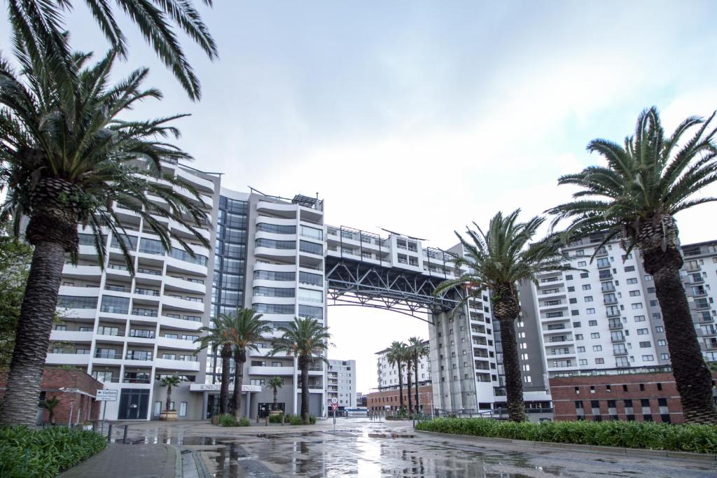 a large building with palm trees in front of it at Citystay Apartments Century City in Cape Town