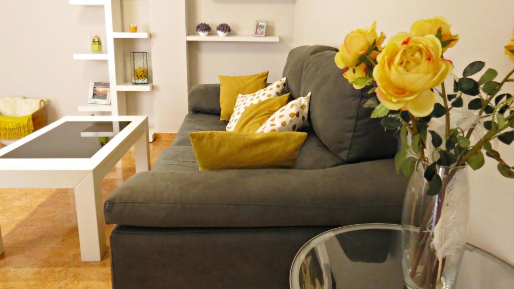 un soggiorno con divano e vaso di fiori gialli di La Sastrería del Realejo a Cordoba