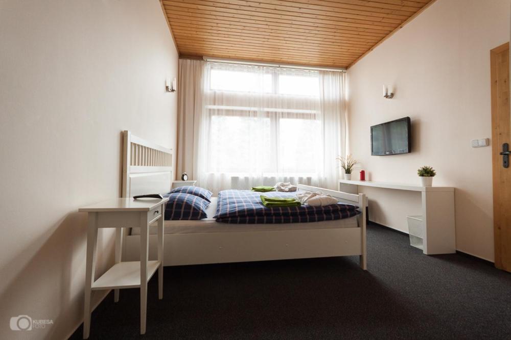 Schlafzimmer mit einem Bett, einem Fenster und einem Schreibtisch in der Unterkunft Hostinec & Vitální svět Raduňka in Opava