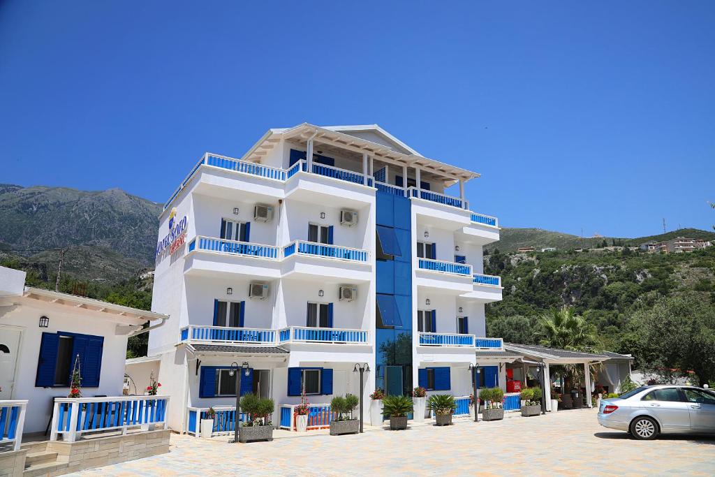 un edificio blu e bianco con un'auto parcheggiata di fronte di Sofo Hotel Dhermi a Dhërmi