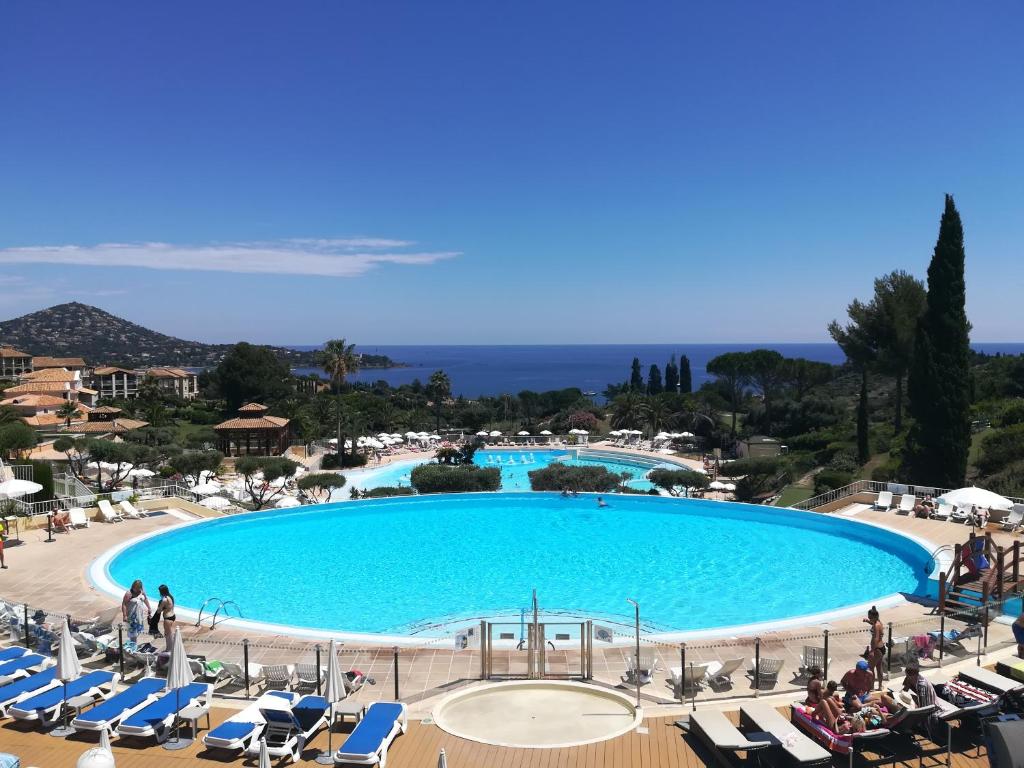 une grande piscine avec des chaises et des fauteuils dans l'établissement CAP ESTEREL appartement climatisé dans le centre du village vacances, à Drammont
