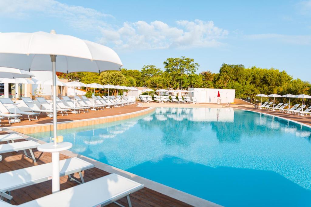 a large swimming pool with white chairs and umbrellas at Torre Cintola Greenblu Sea Emotions in Monopoli