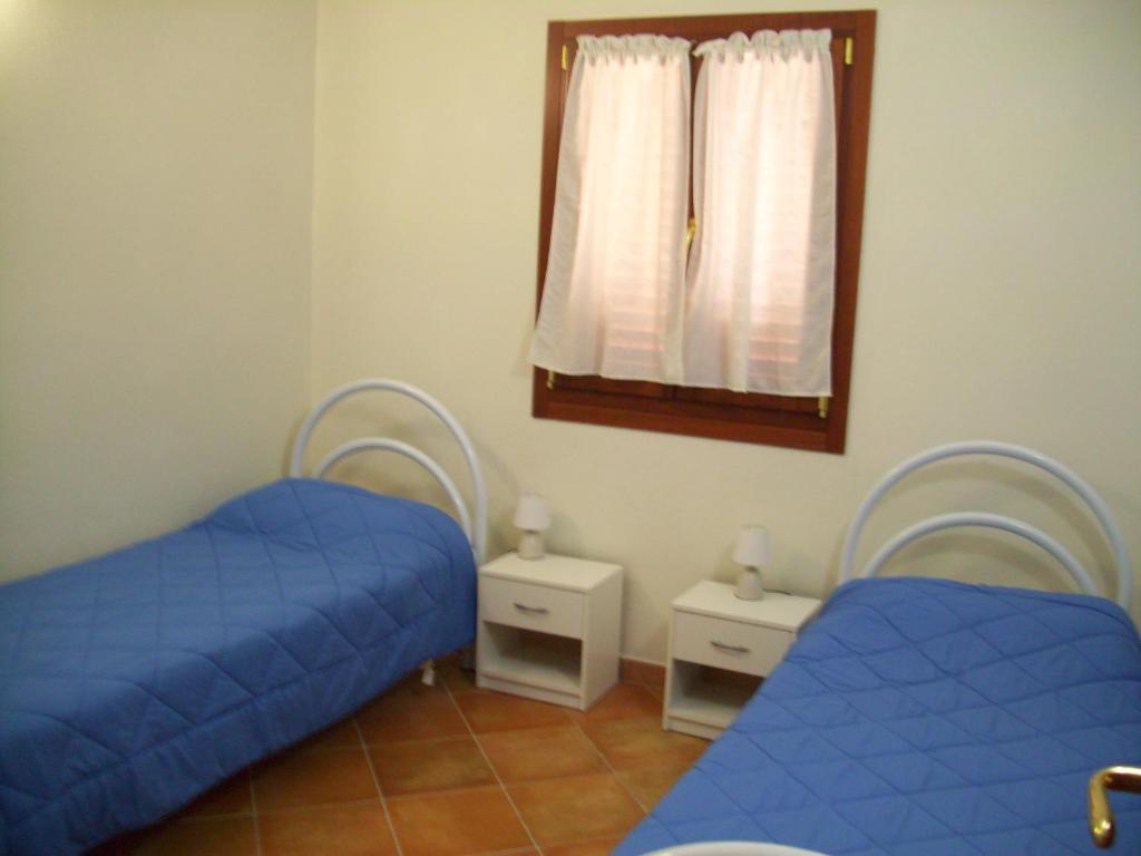 2 camas en una habitación con sábanas azules y espejo en VILLA A 200 METRI DALLA SPIAGGIA, en Budoni