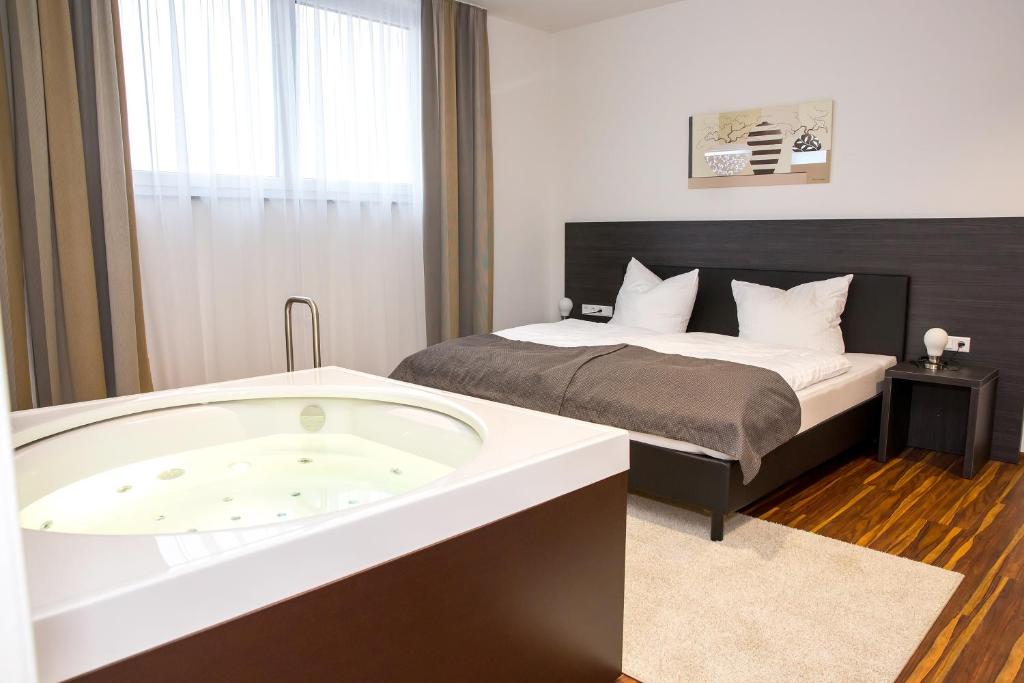 a hotel room with a bath tub and a bed at Plus Punkt Private Spa in Weingarten