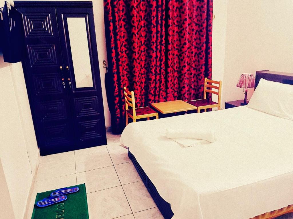 a bedroom with a bed and a door with a red curtain at Sophin Hotel in Sharjah