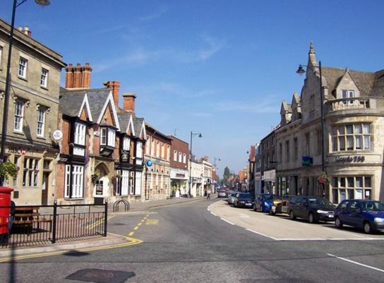 una calle de la ciudad con edificios y coches aparcados en la carretera en Angel at Bourne, en Bourne