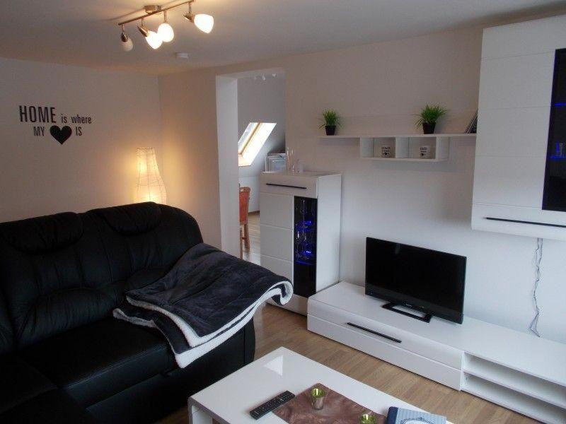 a living room with a black couch and a tv at Janos-Ferienwohnung-2 in Friedrichsbrunn