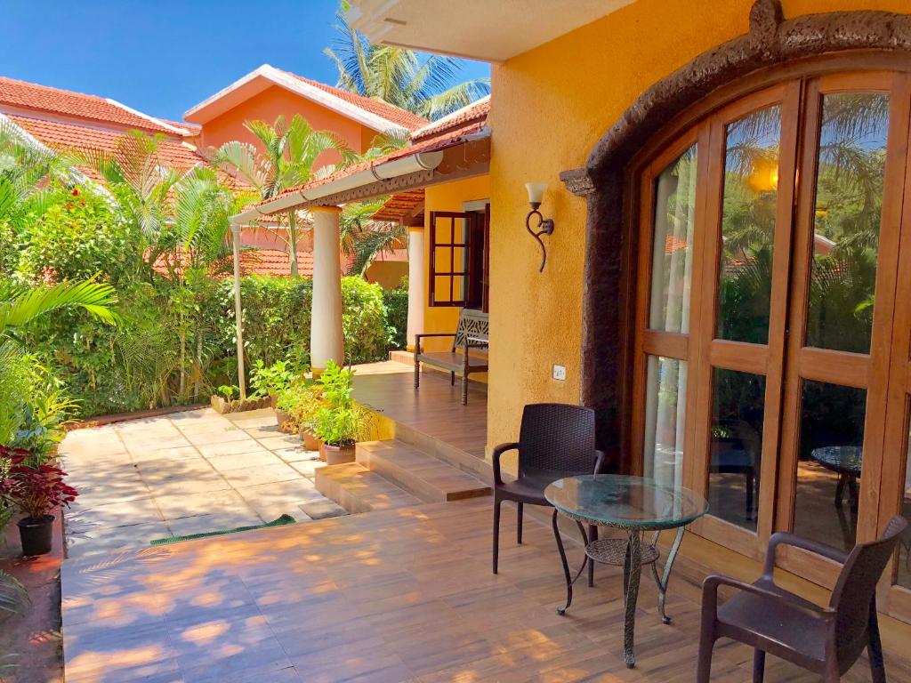 un patio de una casa con mesa de cristal y sillas en The Bungalows Light House, Goa by Leisure Hotels en Candolim