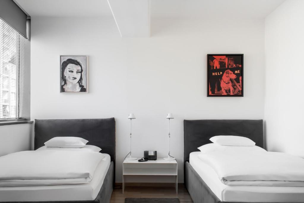 two beds in a room with white walls at Augarten Art Hotel in Graz