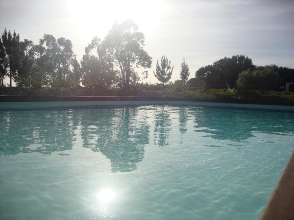 una piscina de agua con el sol reflejándose en ella en Amor de Crianca en São Teotónio