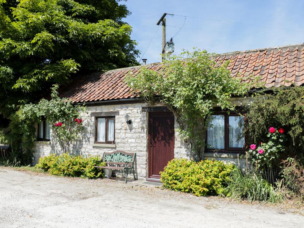 a small stone house with a bench in front of it at Rose Cottage in Great Edston