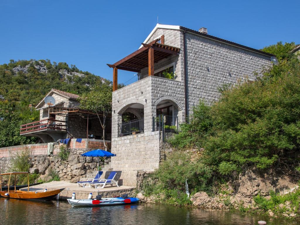 a house on the side of a river with boats at Paradise House Skadar Lake in Karuč
