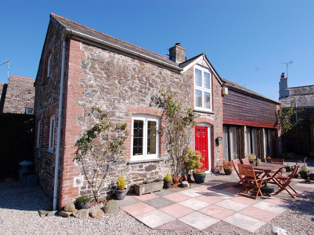 a brick house with a red door and a patio at Jacobs Barn in Lifton