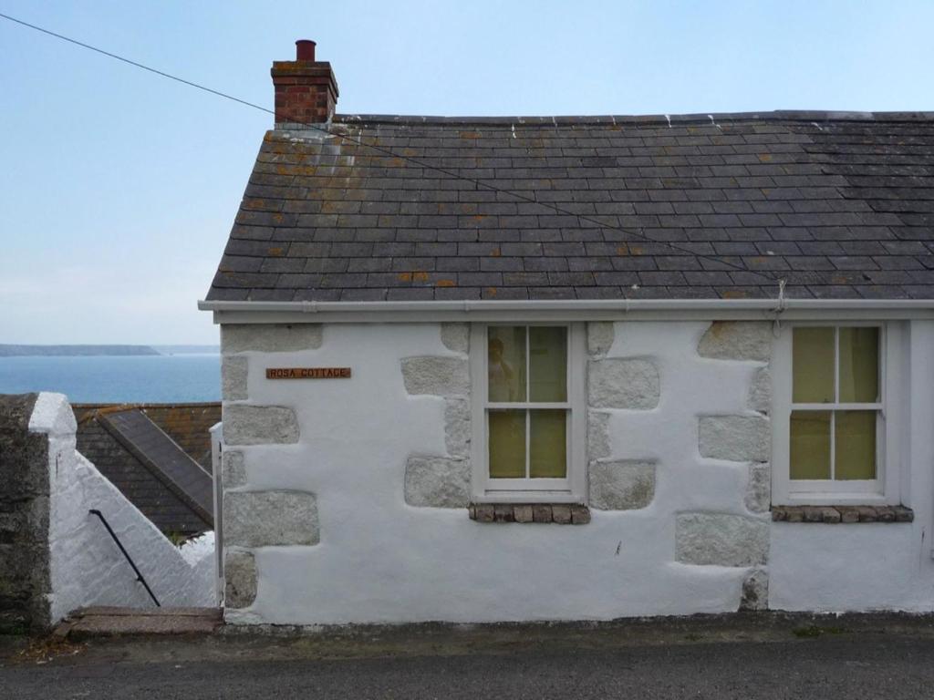 ein weißes Gebäude mit zwei Fenstern und einem Dach in der Unterkunft Rosa Cottage in Porthleven