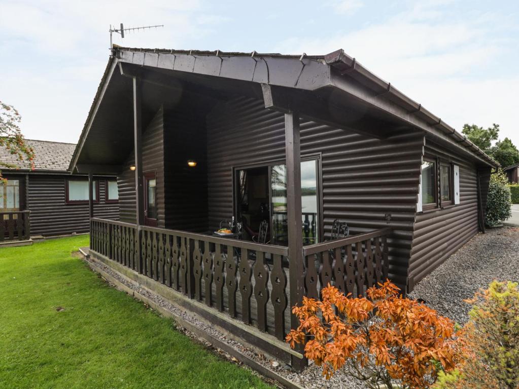 a log cabin with a porch and a fence at Hope Lodge in Carnforth