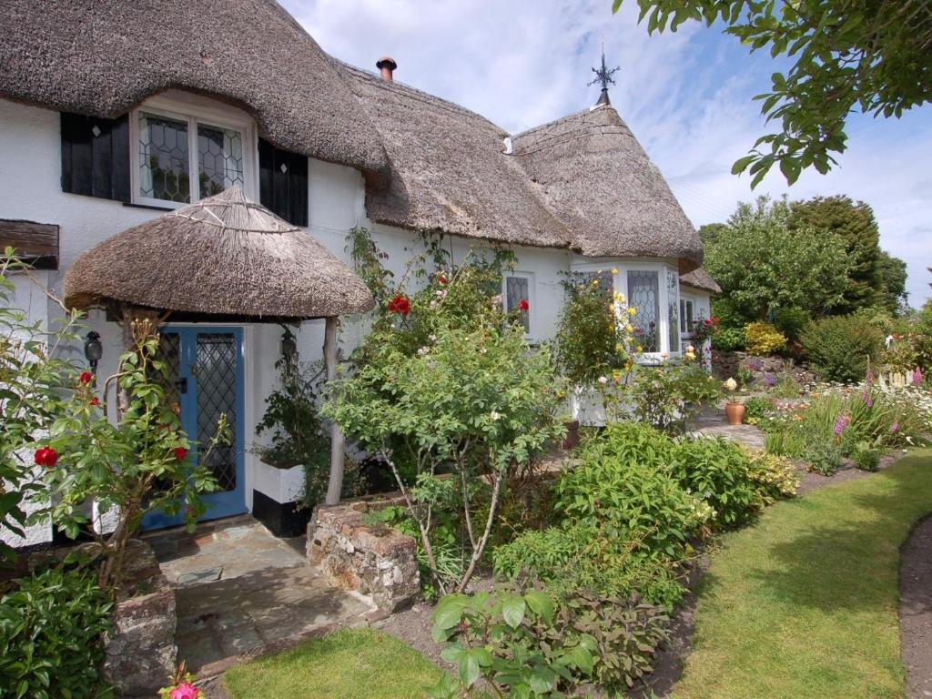 a cottage with a thatched roof and a garden at Appletree Cottage in Ilsington