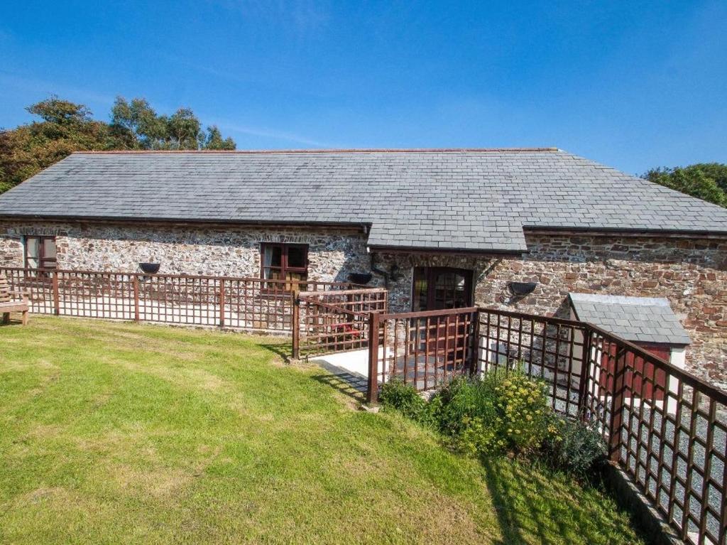 a stone barn with a fence in front of it at Billy's Barn in Bradworthy