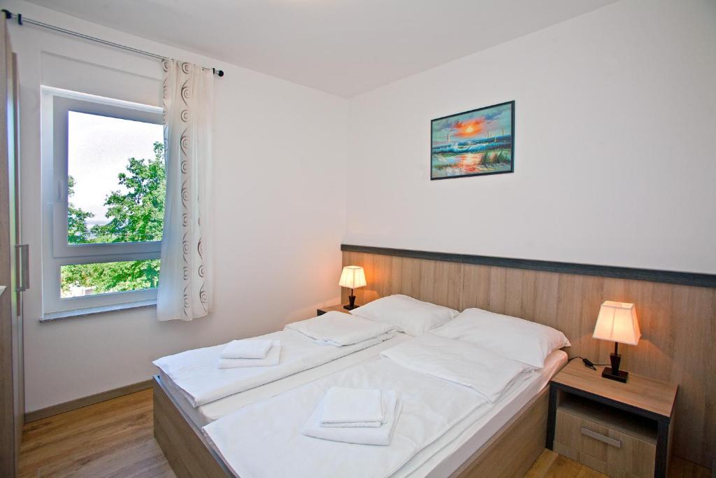 um quarto com uma cama com lençóis brancos e uma janela em Apartments Maslina II em Njivice