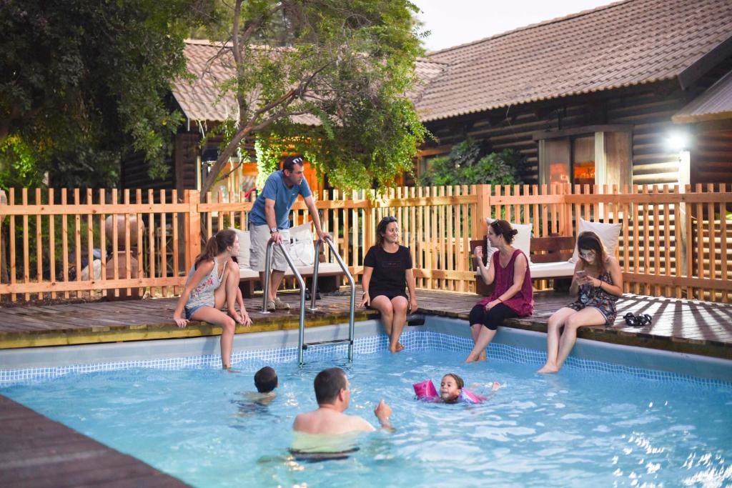 a group of people sitting in a swimming pool at Cabin Resort in Moshav Ramot