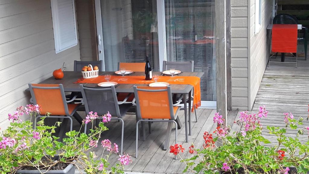 una mesa naranja y sillas en un porche con flores en Le Chant Des Mûres en Plabennec
