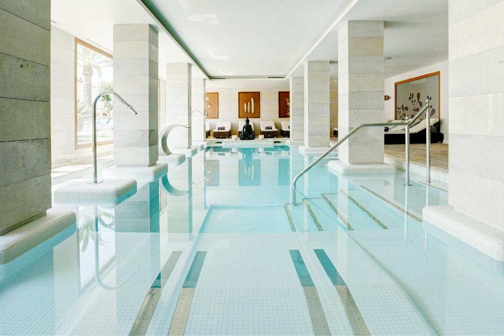 a swimming pool in a house with glass floors at Grupotel Los Príncipes & Spa in Playa de Muro