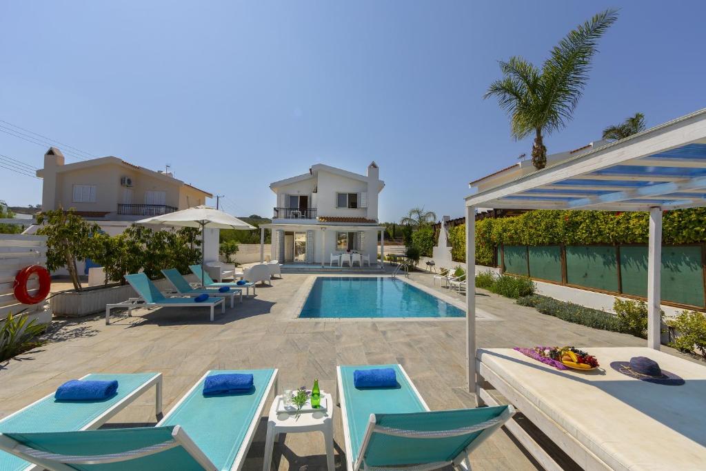 een villa met een zwembad en blauwe stoelen bij Fig Tree Bay Villa 3 in Protaras